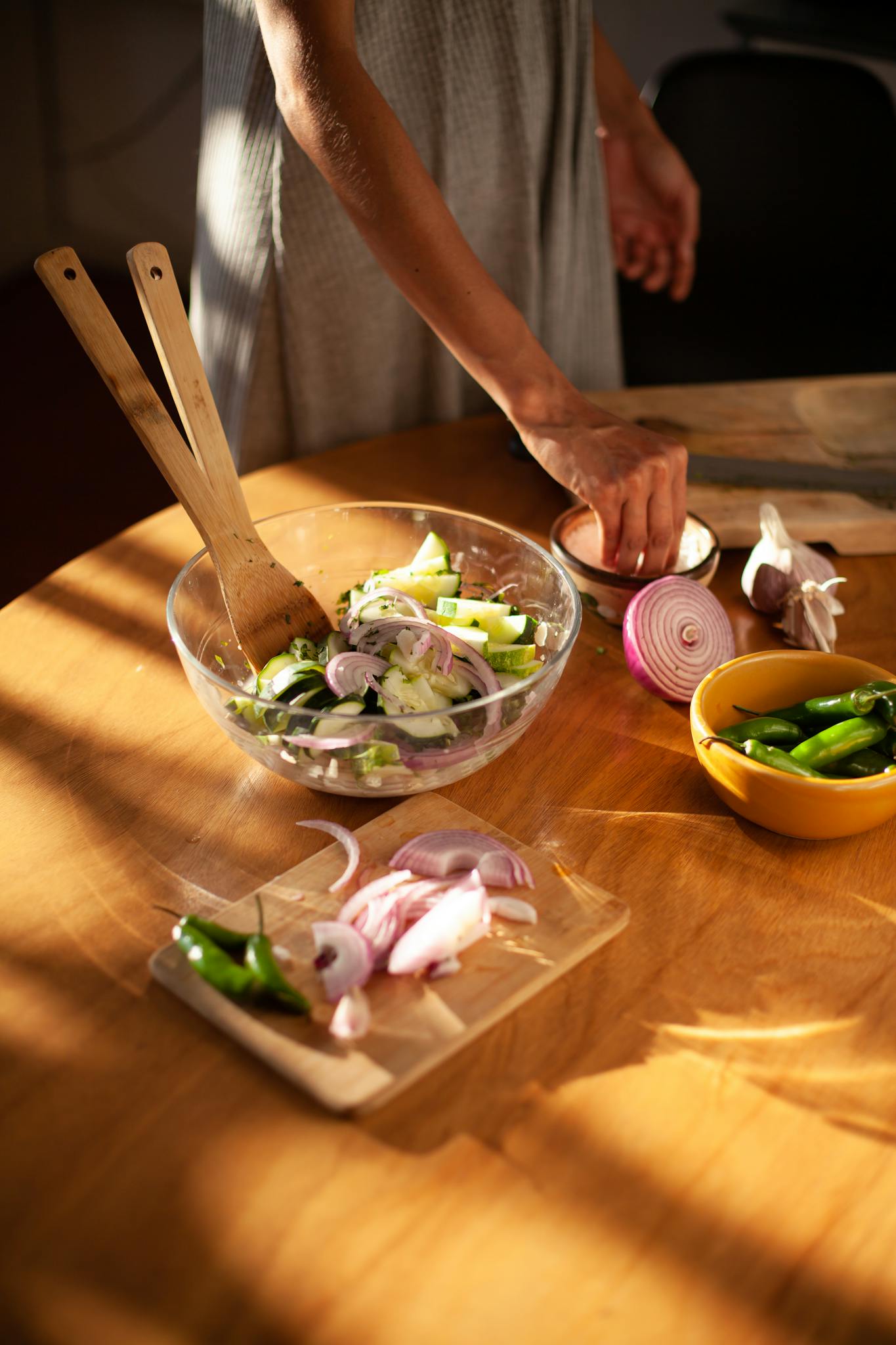 A close-up view of fresh vegetable salad preparation with zucchini and onions in a kitchen setting.